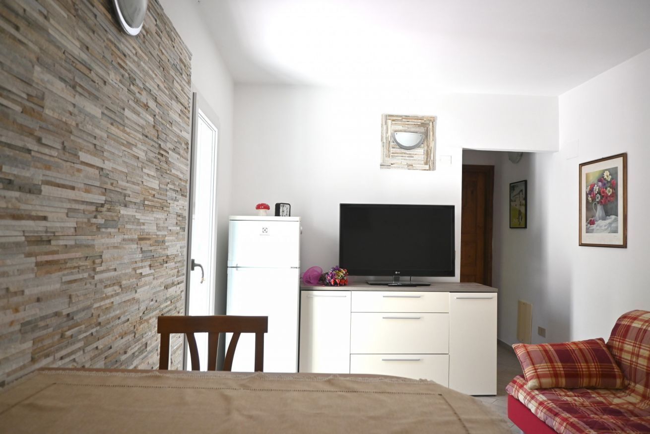 Ein Schlafzimmer mit Bett, Fernseher, Kleiderschrank, Sessel und Sofa.