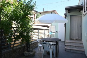 A patio with a table and chairs, a white umbrella, and a stone wall. - SE285 - Senigallia, bright one-bedroom apartment with an outdoor courtyard, just a short walk from the center of Senigallia (Senigallia)