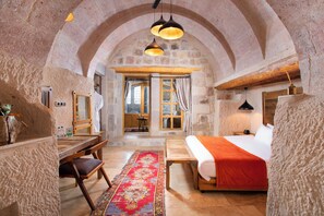 Ein rustikaler Raum mit einem Bett, Holzmöbeln, einem Teppich und Steinwänden.