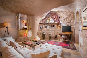 Un salon chaleureux avec un décor intérieur en pierre, une cheminée, un téléviseur et un coin repas comprenant une table et des chaises.