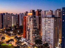 Un edificio alto con varios pisos, rodeado de otros edificios.