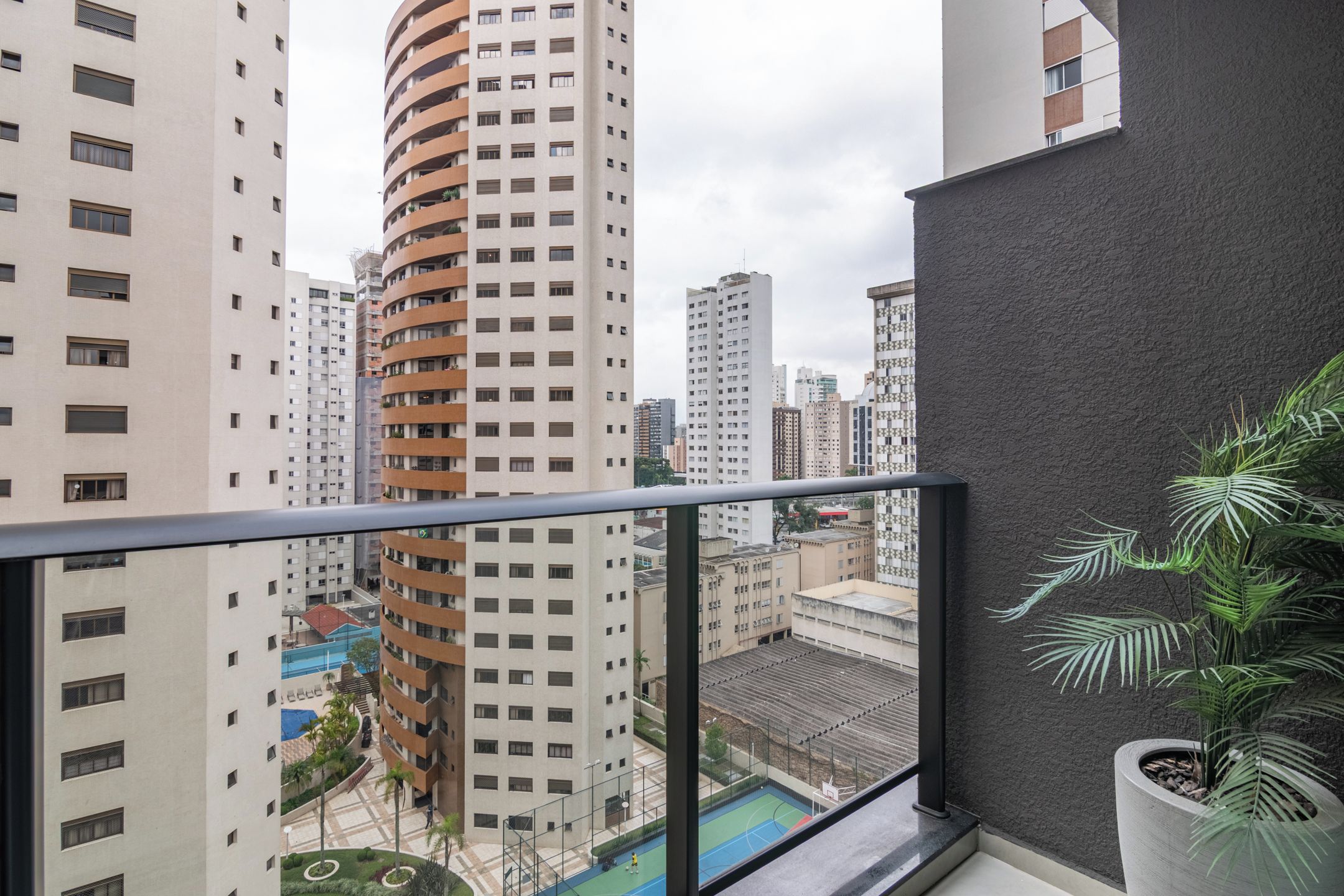 A high-rise building with a curved facade, a rooftop pool, and a view of other buildings.