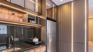 A modern kitchen with a built-in microwave, a stainless steel refrigerator, and a granite countertop.