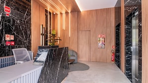 A reception area with a marble counter, a seating area, and a wooden panel wall.