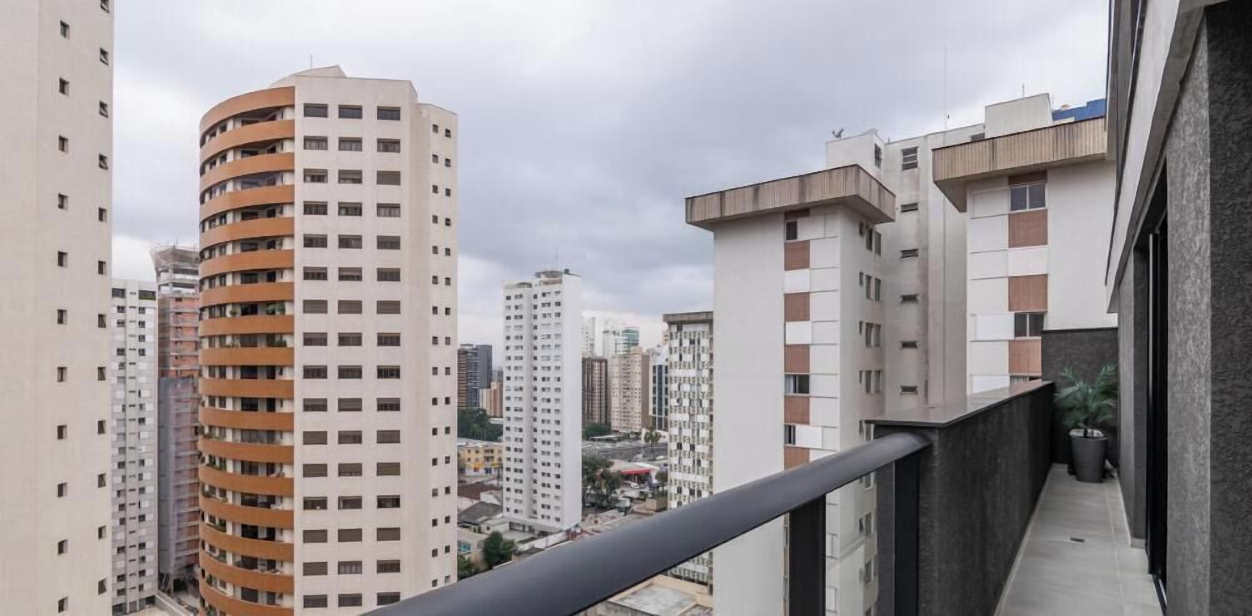 A high-rise building with multiple balconies, a clear sky, and other surrounding buildings.