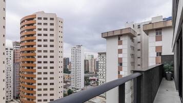 A high-rise building with multiple balconies, a clear sky, and other surrounding buildings.