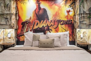 Une chambre à coucher avec un lit, des oreillers et un mur orné d’une affiche de film.