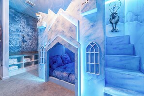 Ein Kinderzimmer mit Bett, fest eingebauten Regalen und Wandmalerei.