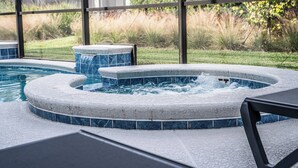Ein Whirlpoolbereich mit Pool, umgeben von einer Glaseinfassung und Blick auf eine grüne Landschaft.
