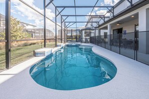 Une piscine intérieure dotée d’une paroi vitrée, un jacuzzi et un espace extérieur aménagé avec des sièges.