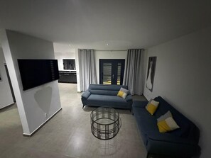 Uma sala de estar moderna com um sofá, uma mesa de centro e uma televisão.