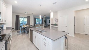Een moderne keuken met een centraal eiland, een zithoek met een bank en uitzicht op de omgeving.