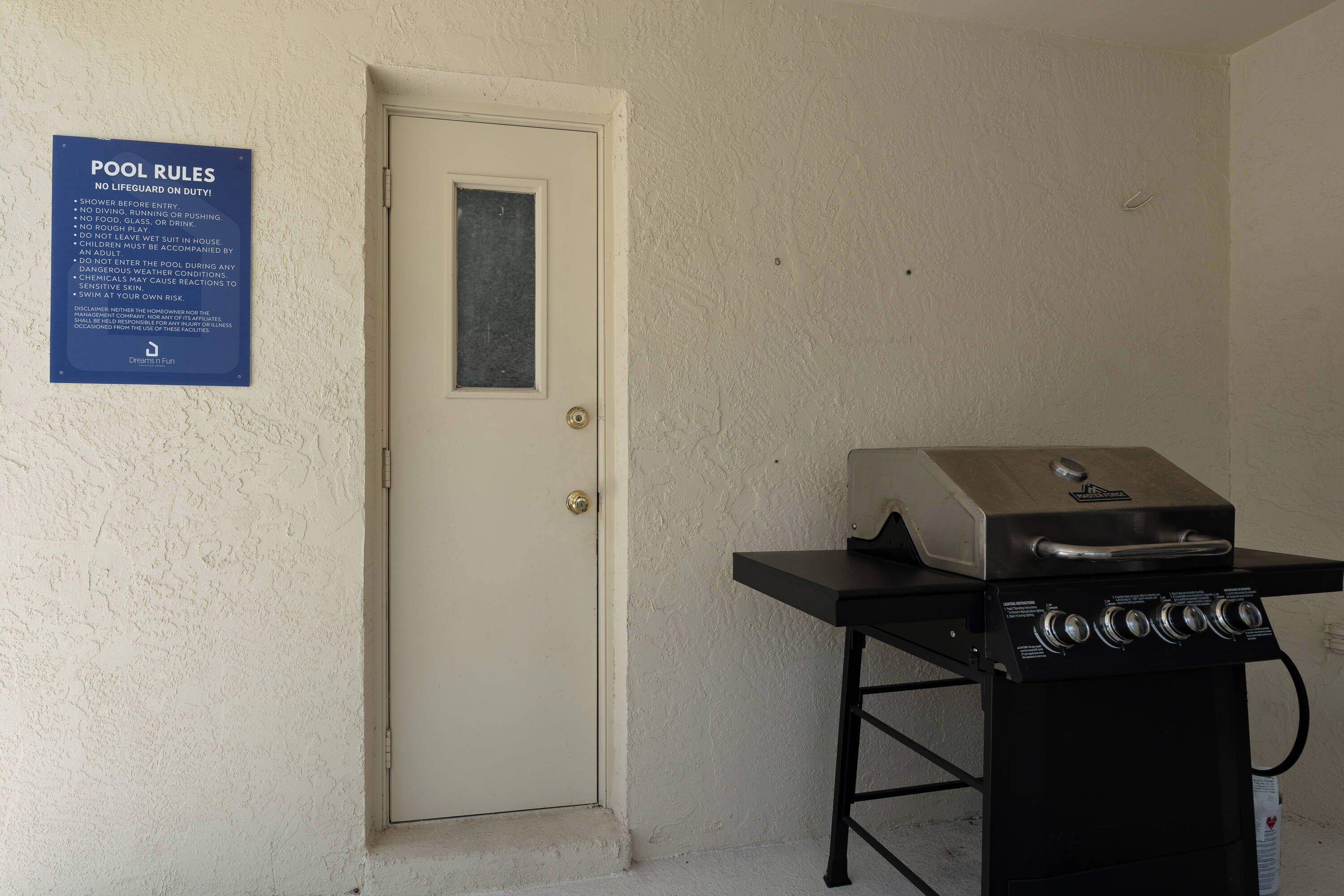 A door with a pool rules sign, a grill, and a textured wall.