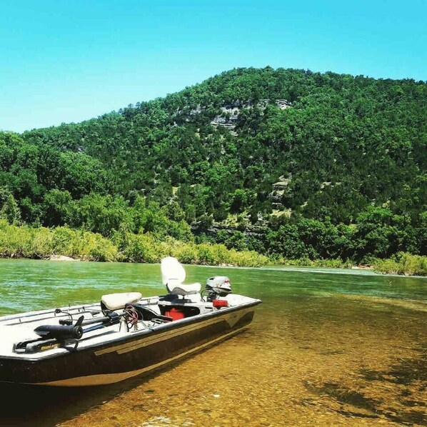 Un barco amarrado en un río, con una colina boscosa al fondo.