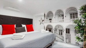 Quarto com cama, almofadas, decoração com estrelas e varanda com arcos.