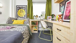 A bedroom with a bed, desk, chair, and a window with curtains. - Unite - Harriet Martineau - Birmingham (Birmingham)