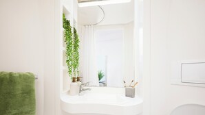 A bathroom with a white sink, a mirror, a green towel, and a potted plant. - Unite - Harriet Martineau - Birmingham (Birmingham)