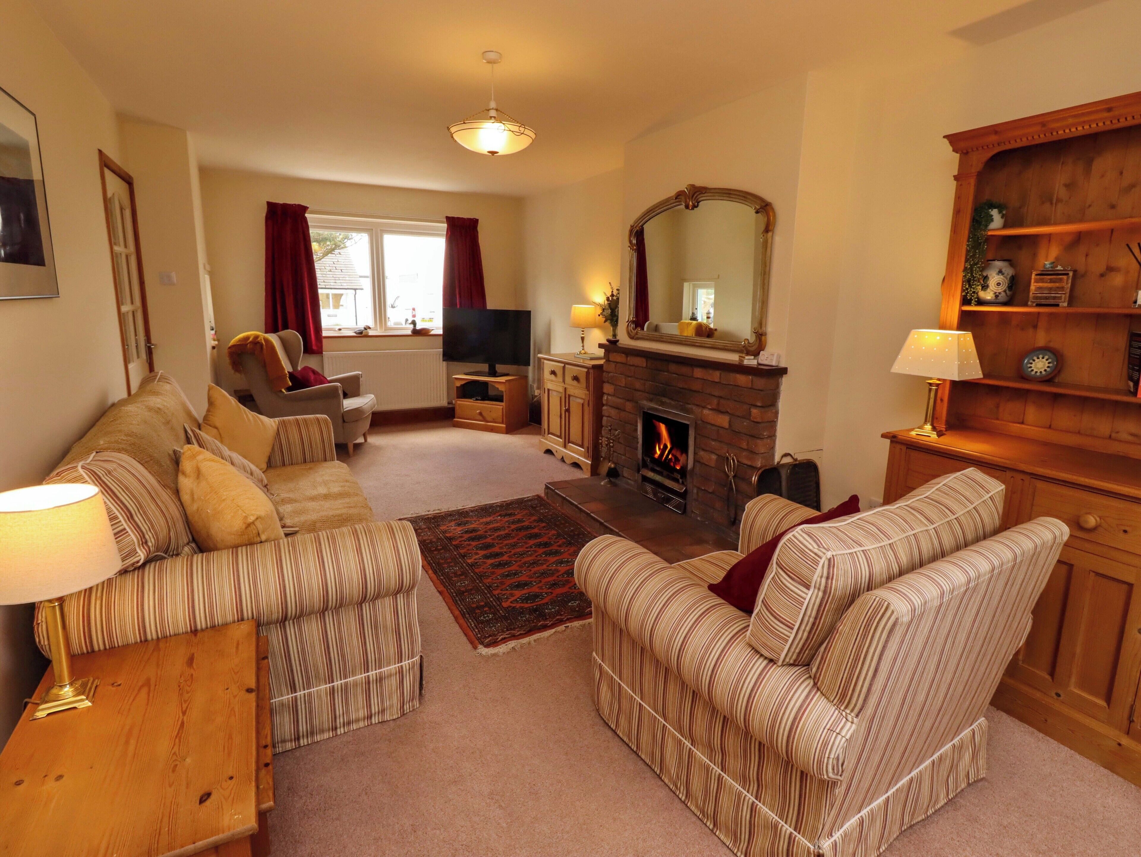 A living room with a fireplace, sofas, a television, and a wooden cabinet.