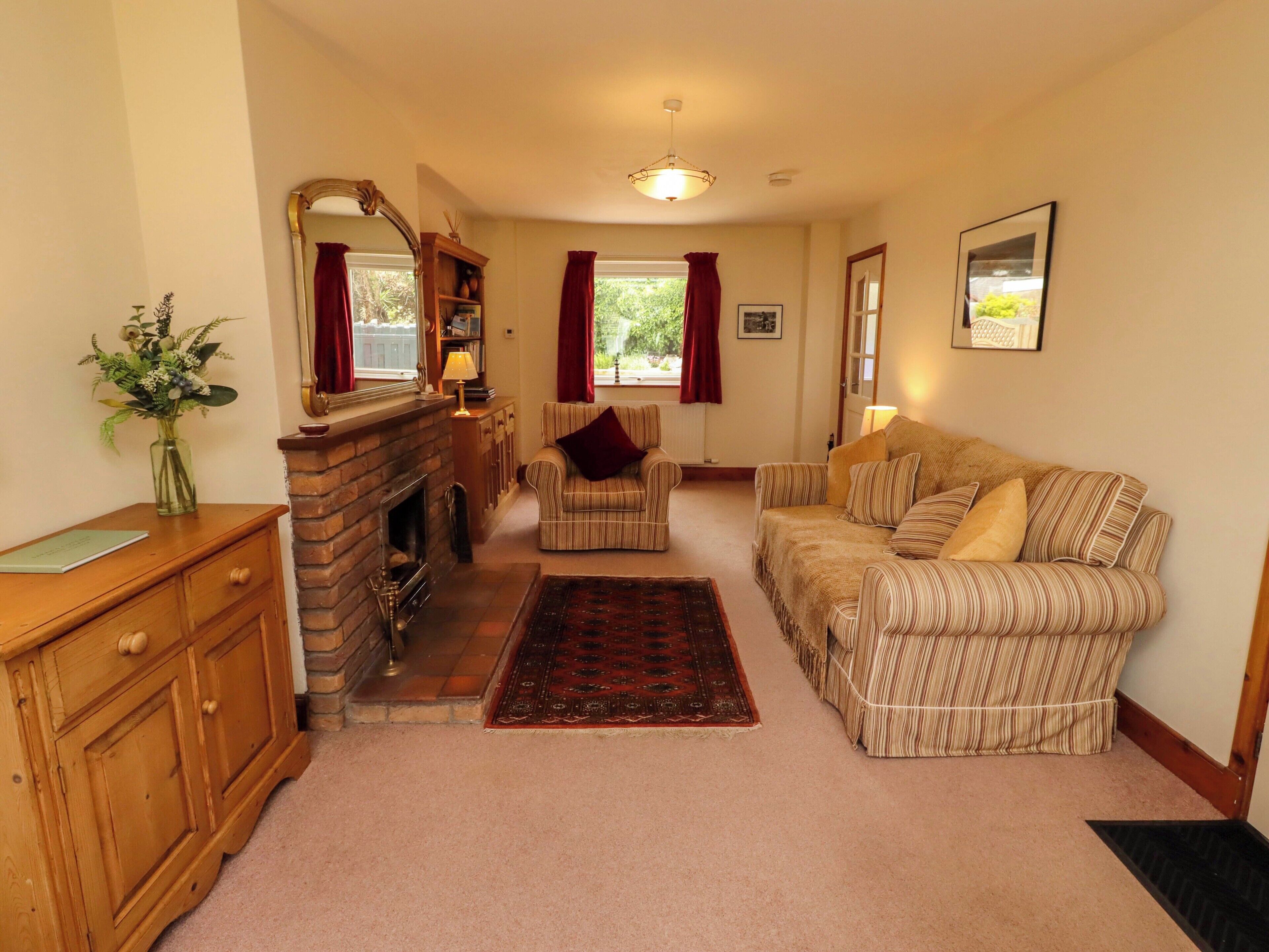 A living room with a fireplace, a sofa, a chair, a wooden cabinet, and a rug.