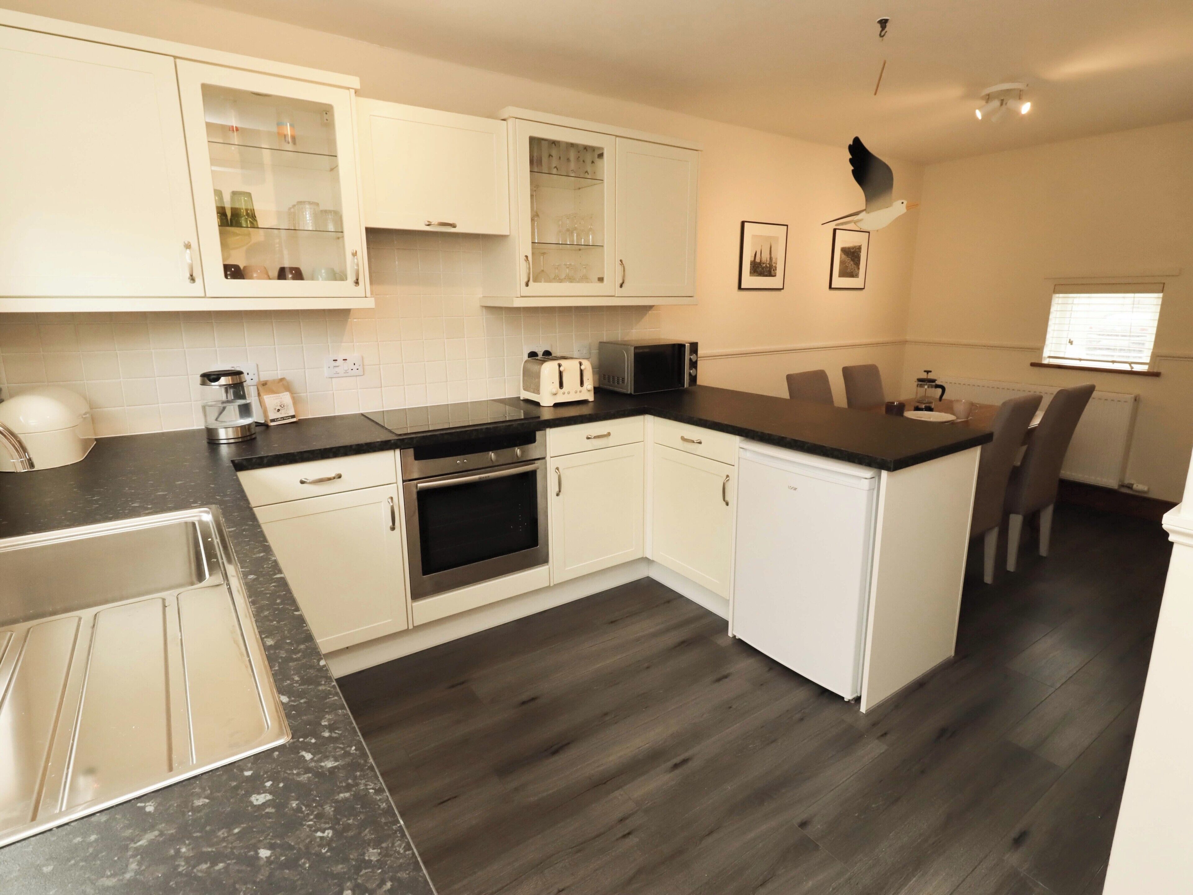 A modern kitchen with white cabinetry, a black countertop, and a built-in oven.