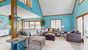 A spacious living room with a large sectional sofa, a coffee table, and a purple armchair. - Keen-Wik on the Bay - 38138 Keenwik Rd (Selbyville)