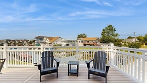 A deck with two chairs and a table, overlooking a marina with boats and houses. - Keen-Wik on the Bay - 38138 Keenwik Rd (Selbyville)