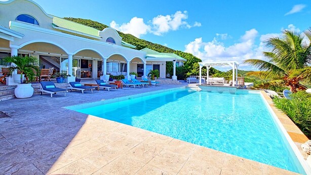 A large swimming pool with lounge chairs, a covered patio, and a view of a lush green hillside. - 300m² villa with a 180° ocean view of St. Barths, Tintamar, and Pinel (st martin     francaise)