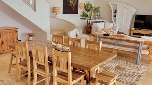 A spacious dining area with a large wooden table and chairs, a staircase, a mounted painting, and a television. - 300m² villa with a 180° ocean view of St. Barths, Tintamar, and Pinel (st martin     francaise)