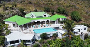 Une grande maison dotée d’une piscine, de nombreux balcons et d’un jardin luxuriant.