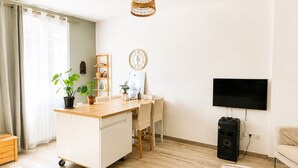 Una sala de estar con un escritorio de madera, televisor, parlante y comedor con sillas y mesa.