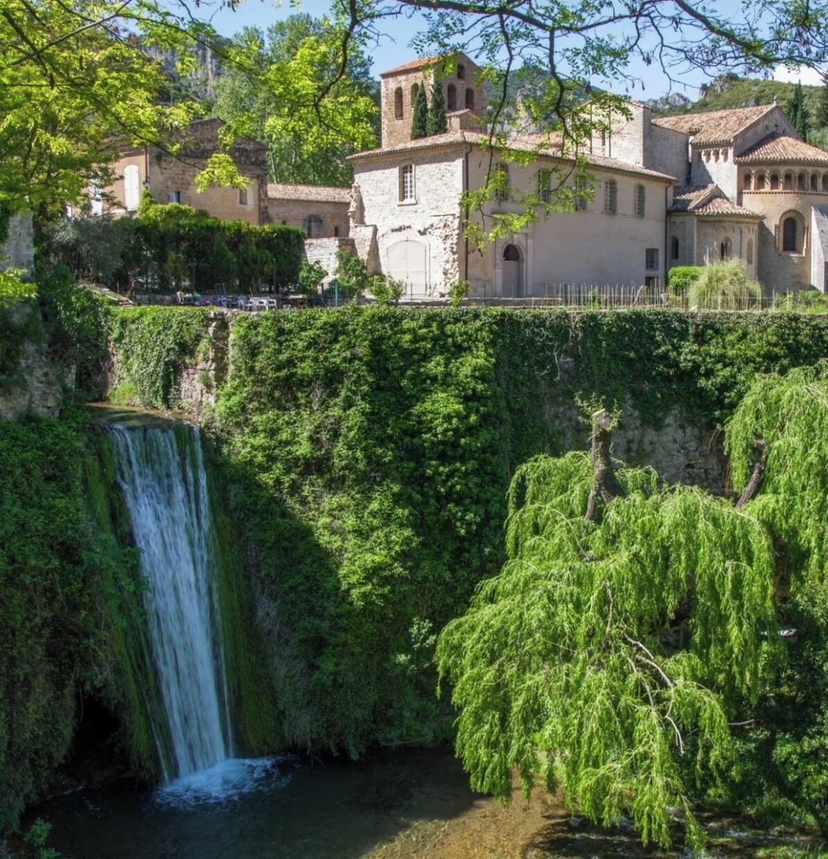 A waterfall, lush greenery, and traditional stone buildings.