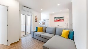 A modern living room with a grey sofa, a flat-screen TV, and a painting on the wall. - Casa Oceano Apartment with Wi-Fi and Air Conditioning (Armação de Pêra)
