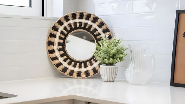 A round woven mirror, a potted plant, and a clear vase on a white countertop. - Casa Oceano Apartment with Wi-Fi and Air Conditioning (Armação de Pêra)
