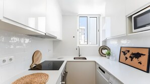 A modern kitchen with white cabinetry, a built-in stove, a sink, and a microwave. - Casa Oceano Apartment with Wi-Fi and Air Conditioning (Armação de Pêra)