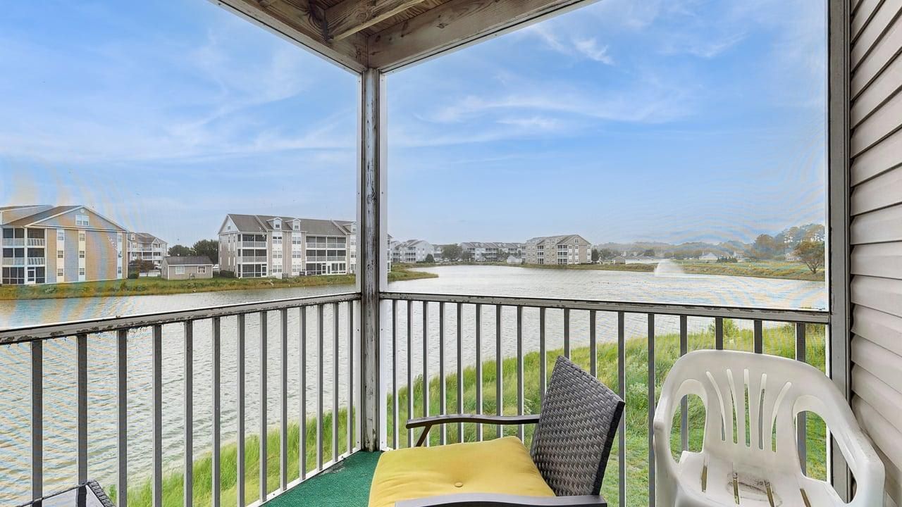A balcony with a view of a river and buildings across it.