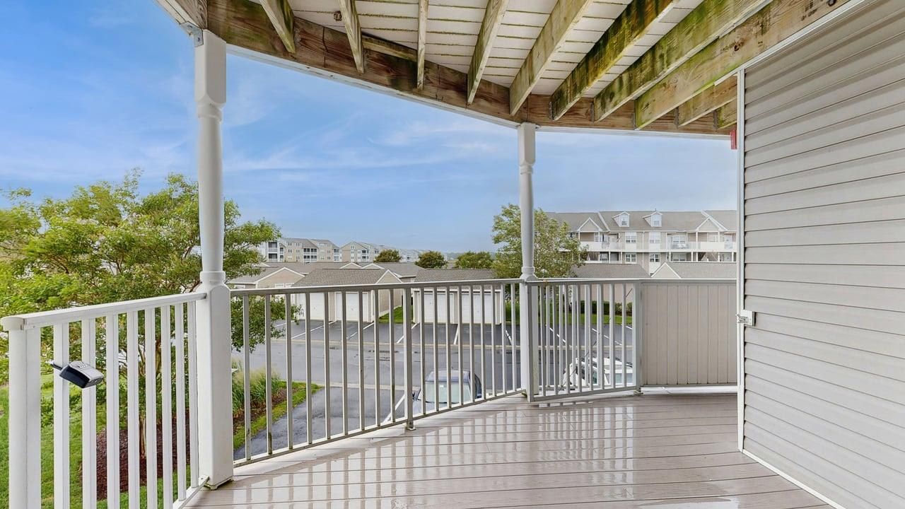 En overdækket balkon med udsigt over en parkeringsplads og boligbygninger.
