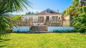 A two-story house with a front porch, a small garden, and a wooden fence. - Hazeldene -  a cottage that sleeps 8 guests  in 3 bedrooms (Shanklin)