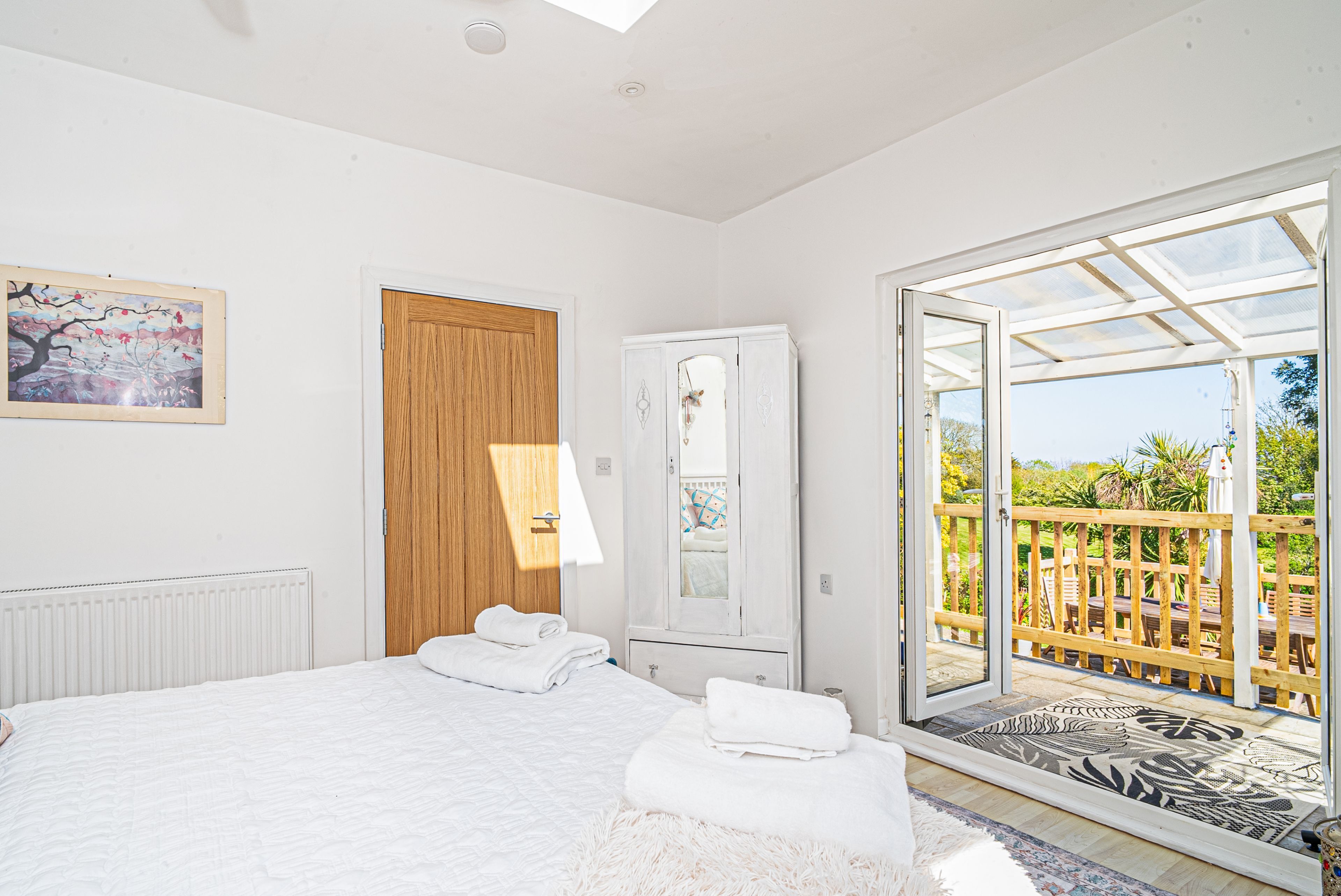 Un dormitorio con cama, puerta de madera, armario y balcón con vistas.