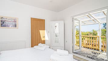 Un dormitorio con cama, puerta de madera, armario y balcón con vistas.