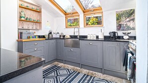 A modern kitchen with grey cabinets, a black countertop, a skylight, and a patterned rug. - Hazeldene -  a cottage that sleeps 8 guests  in 3 bedrooms (Shanklin)