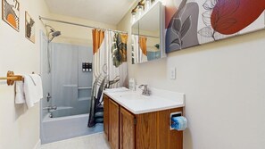 Une salle de bain avec une douche, un lavabo et un miroir.