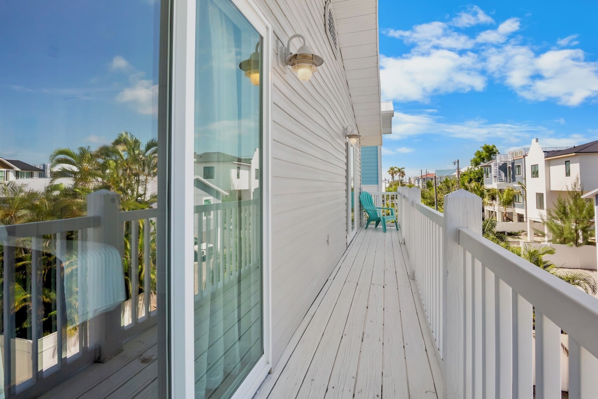 A balcony with a view of neighboring houses, a railing, and a clear sky.
