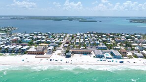 A coastal resort with beachfront properties, a central building with a pool, and a view of the ocean. - Midnight Gulf Resort A (Bradenton Beach)