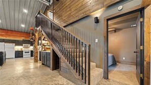A spacious kitchen with modern appliances, a wooden staircase, and a cozy living area. - Barndominium Near Mt. Magazine & Lake Access (New Blaine)