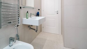 A modern bathroom with a white sink, mirror, and towel rack.