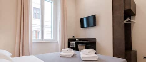 A modern hotel room with a large bed, a flat-screen TV, a desk, and a wardrobe.
