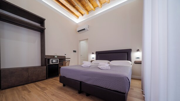 A bedroom with a bed, bedside tables, a desk, a chair, a wardrobe, and a ceiling light.