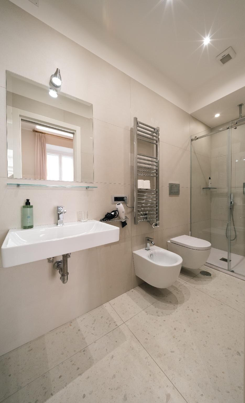 Et moderne badeværelse med vask, toiletbidét og glasbrusekabine.
