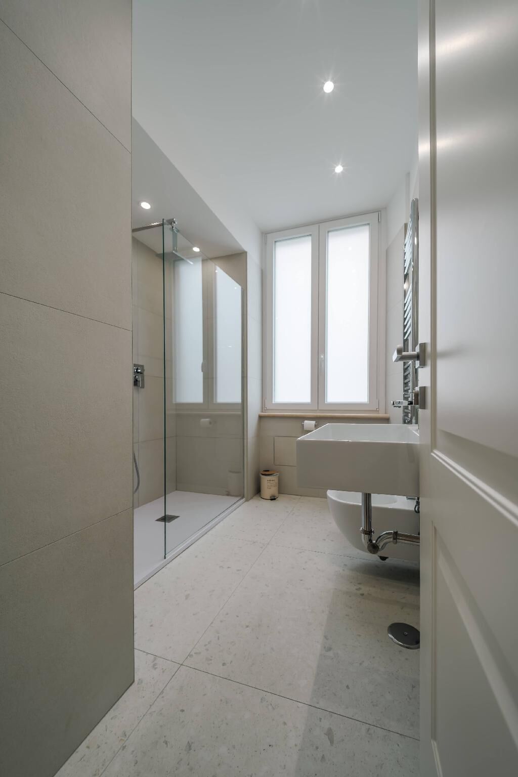 Une salle de bain moderne avec une douche à parois de verre, une grande fenêtre et un lavabo avec un miroir.