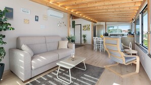 Una sala de estar moderna con un sofá, techo de madera y vista al exterior.